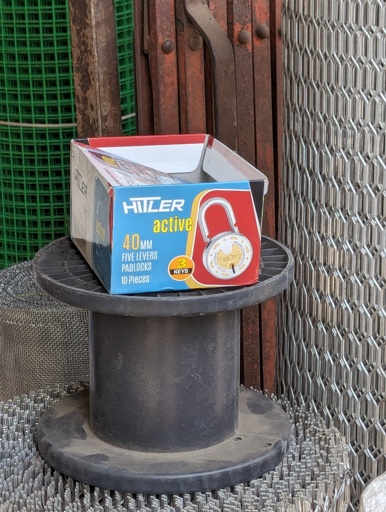 An empty cardboard box sits discarded in an Indian shop. The box was for padlocks and is "HITLER" brand.